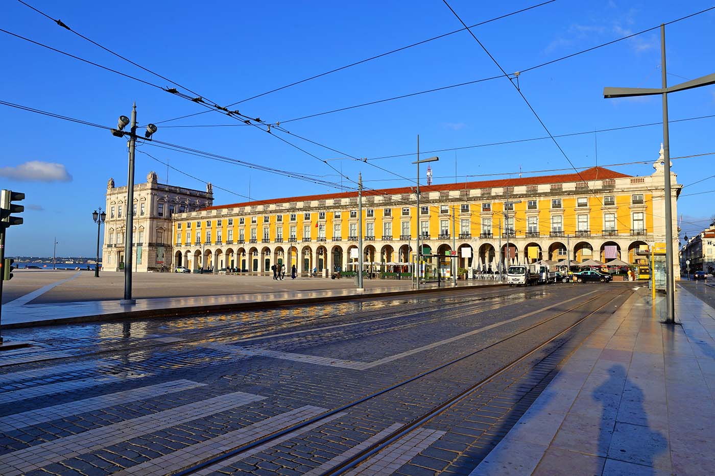 Gele gevels van Praça do Comércio met tramrails op de voorgrond